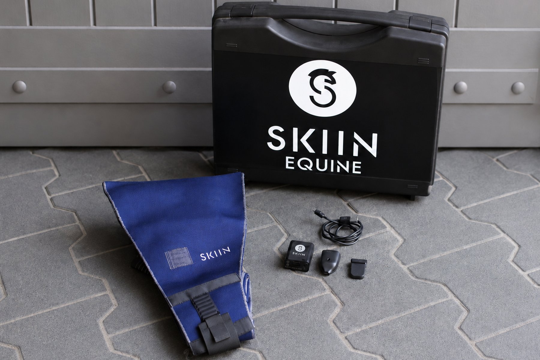 The SKIIN Equine kit laid out: textile band, electronic pod, sensors, charging cable and carry case